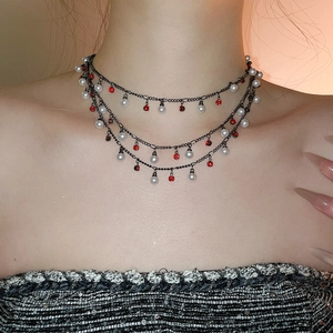 Close-up of triple-layered choker with white pearls and red crystals on black chain