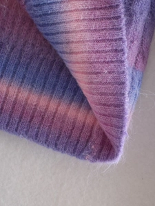 Macro shot of soft gradient tie-dye knit fabric in purple, pink, and blue tones