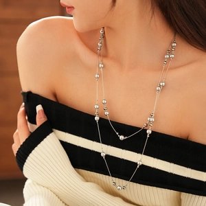 Detail of layered silver-grey beaded necklaces on model with elegant French vintage style
