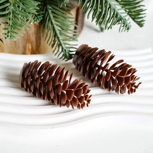 Artificial brown pine cones on a white tray with pine needles for Christmas decoration