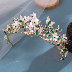 Detail of bridal tiara featuring golden leaves, white flowers and green crystals