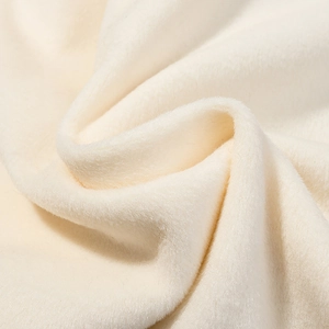 Gros plan sur la texture du tissu en laine beige doux montrant les fibres pelucheuses