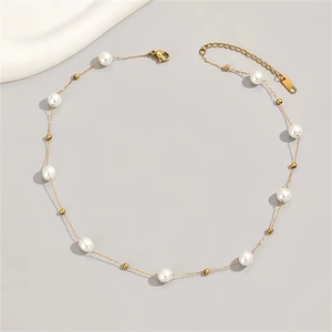 Elegant pearl necklace with gold beads and fine chain on a minimalist gray background