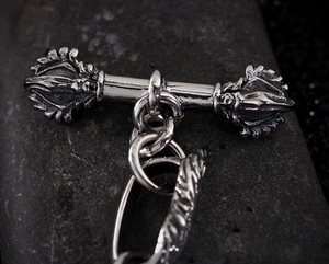 Macro view of silver steel Vajra pestle accessory on a textured dark background