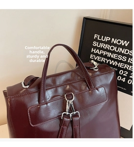 Detail view of burgundy shiny leather backpack with silver metal hooks and sturdy handle
