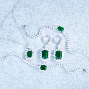 Luxury emerald-cut jewelry set with necklace, bracelet and earrings on grey background
