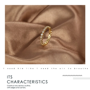 Macro shot of gold eternity ring with white cubic zirconia on silk fabric background