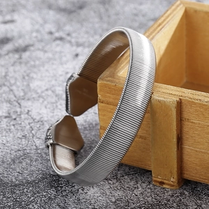 Detailed view of punk snake head steel bracelet resting on a wooden box with metal texture