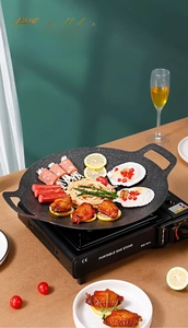 Close-up of portable gas stove with stone-coated grill pan featuring grilled seafood and meat