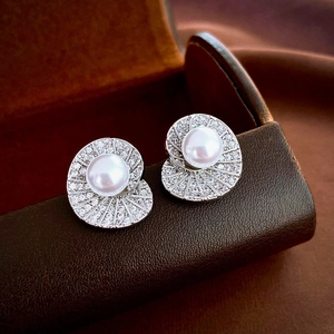 Macro shot of silver shell earrings with a central pearl and radiating rhinestones