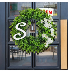 Detail of eucalyptus Christmas wreath with metal lantern and letter S on a door