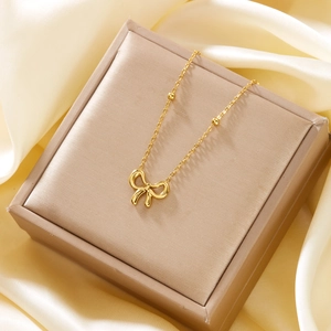 Detailed view of an 18K gold bow pendant necklace resting in a premium gift box