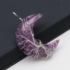 Macro shot of silver wire-wrapped crescent moon pendant filled with amethyst crystal stones