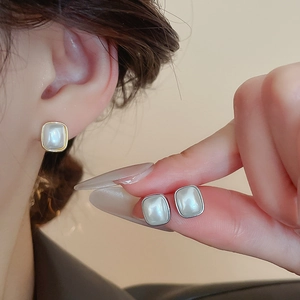 Détail de boucles d'oreilles perles carrées montrant le rendu porté sur un mannequin
