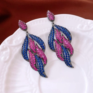 Macro view of vintage leaf drop earrings with pink and blue zircons on a ceramic plate