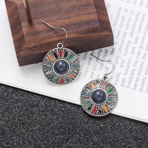 Macro detail of Bohemian sunburst drop earrings with colorful enamel and blue bead