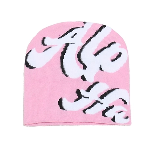Close-up of pink knit beanie showing detailed letter jacquard pattern and warm wool texture