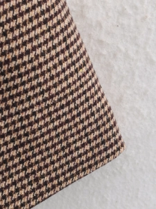 Close-up detail of the brown houndstooth pattern fabric on this mid-length blazer coat