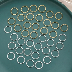 Textured gold and silver jump rings for DIY jewelry making displayed on a green plate