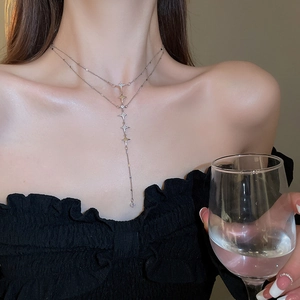 Close-up of double-layer silver star tassel necklace worn on model neck