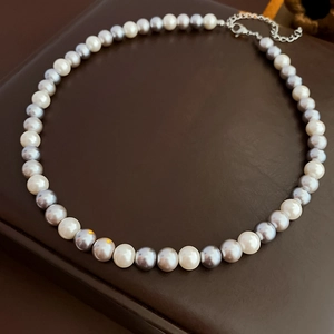 Detailed view of bicolor pearl necklace with white and grey pearls and metal clasp