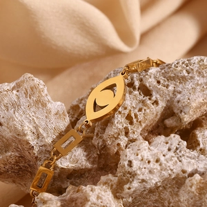 Close-up of 18K gold plated evil eye bracelet on coral and soft silk background