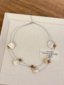 Detail of double-layer necklace featuring irregular shell fragments and amber beads