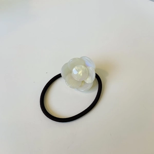 Black elastic hair tie featuring a white resin camellia flower charm on a white background