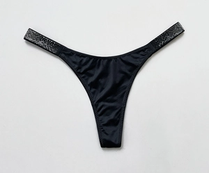 Close-up of black G-string featuring shimmering rhinestone straps and silky fabric texture