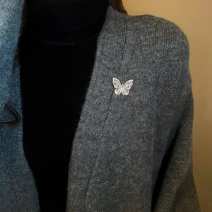Detail of butterfly brooch with water drop zircons worn on a grey knit cardigan lapel