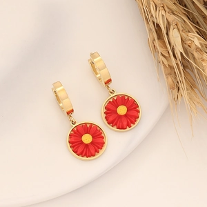 Daisy hoop earrings with red and yellow petals and gold-toned hardware on white ceramic