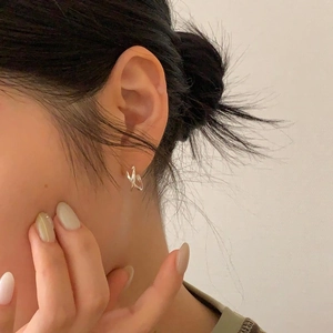 Close-up of minimalist 925 sterling silver earrings with twisted cross line design