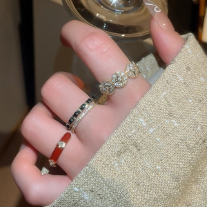 Detailed view of layered 14k gold plated rings with red enamel and zircon on a hand