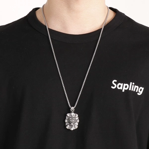 Close-up of vintage steel tiger head and skull pendant on a classic box chain