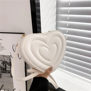 White heart-shaped crossbody bag with triple quilted design and gold metal hardware