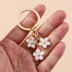 Detailed view of gold sakura keychain with white enamel cherry blossom charms for bags