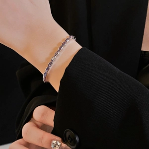 Close-up of geometric silver bracelet with purple zircon stones on a model wrist