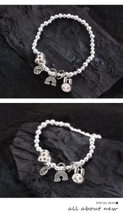 Detailed close-up of a silver beaded bracelet with heart, rabbit, and Fu character charms