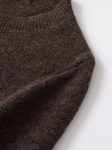 Detail of dark brown knit sweater featuring ribbed crew neck and premium wool texture