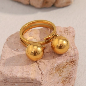 Polished 18K gold plated stainless steel double ball ring on natural stone background