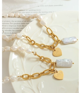 Close-up of Baroque pearl bracelets with gold heart charms on a decorative white plate