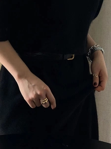 Detail shot of 925 sterling silver golden twisted rings and metallic chunky chain bracelets