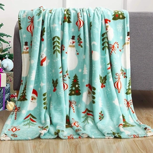 Soft blue Christmas flannel blanket with festive Santa and snowman patterns on a cozy sofa