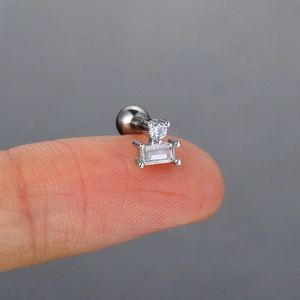 Primer plano de pendiente de acero de titanio plateado con circonitas sobre la yema del dedo