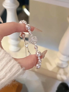 Détail de la fleur en zircon et du bracelet en perles roses avec fermoir ajustable