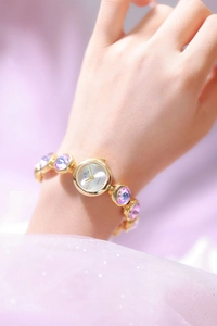 Détail d'une montre dorée de luxe avec cristaux violets sur bracelet à maillons