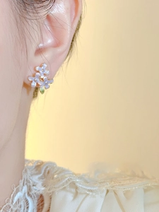 Detailed view of lilac flower stud earrings with enamel finish on a model ear