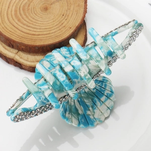 Detailed macro view of sky blue marble acetate hair claw with rhinestones on wood base