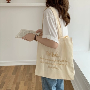 Detailansicht der cremefarbenen Canvas-Tasche mit braunem Bebe-Stickereispruch