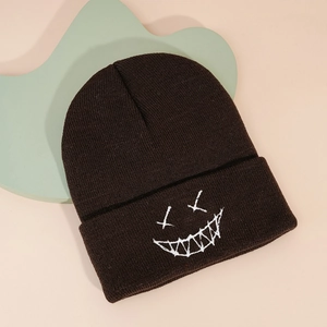 Detailed view of dark brown knit beanie with white embroidered edgy smile pattern